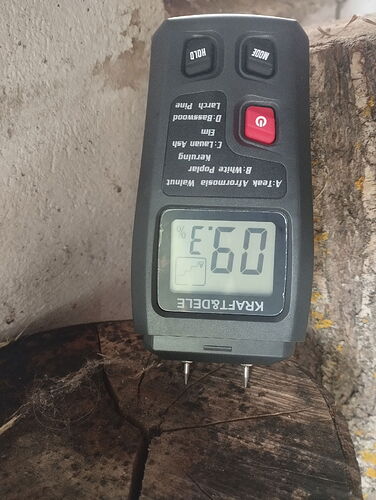 Egy kézi nedvességmérő eszköz fadarabon méri a fa nedvességtartalmát, amelynek kijelzője 09-et mutat. (Feliratozva AI-val)