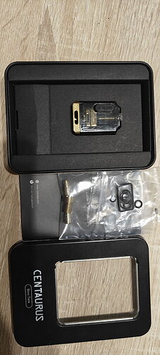 L'image montre une boîte noire dans laquelle se trouve une pièce dorée et quelques accessoires. (Légende par IA)