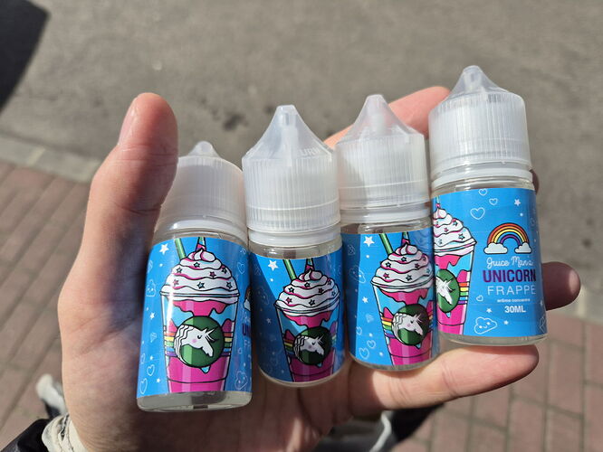 Four flavored liquid bottles with colorful and playful labels, bearing the inscription "Unicorn Frappé". (Labeled by AI)