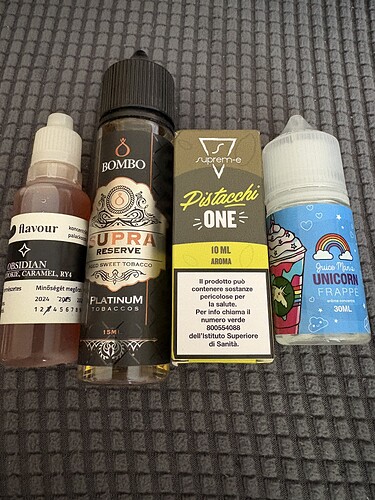 Four different aroma or e-liquid bottles stand upright on a gray, patterned surface. (Labeled with AI)