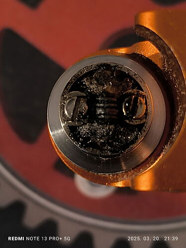 The image shows a metal part, whose surface is dirty, and there is a screw head in the middle. (Captioning by AI)