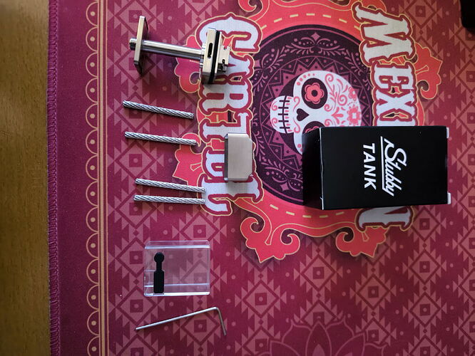 The image shows various parts and tools needed to assemble a tank, with a decorative tablecloth in the background. (Autogenerated by AI)