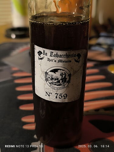 Az üvegben sötét színű folyadék van egy vintage stílusú címkével, amelyen "La Tabaccheria Dell' Ammazzoni" és "N° 759" olvasható. (Feliratozva AI-val)