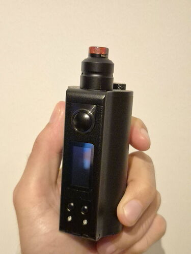 Une main tenant un vaporisateur noir avec écran numérique et boutons (Légendé par IA)