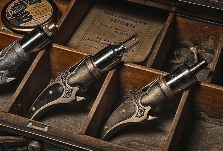 Sur la photo, on voit des appareils de cigarette électronique de style vintage en forme de pistolet dans un rangement en bois compartimenté et une vieille boîte. (Étiqueté par IA)